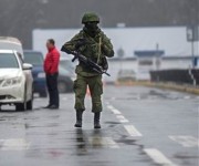 An unidentified armed man patrols a square in front of the airport in Simferopol, Ukraine, Friday, Feb. 28, 2014. Russian military were blocking the airport in the Black Sea port of Sevastopol in Crimea near the Russian naval base while unidentified men were patrolling another airport serving the regional capital, Ukraine's new Interior Minister Arsen Avakov said on Friday. (AP Photo/Andrew Lubimov)