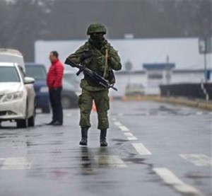 An unidentified armed man patrols a square in front of the airport in Simferopol, Ukraine, Friday, Feb. 28, 2014. Russian military were blocking the airport in the Black Sea port of Sevastopol in Crimea near the Russian naval base while unidentified men were patrolling another airport serving the regional capital, Ukraine's new Interior Minister Arsen Avakov said on Friday. (AP Photo/Andrew Lubimov)